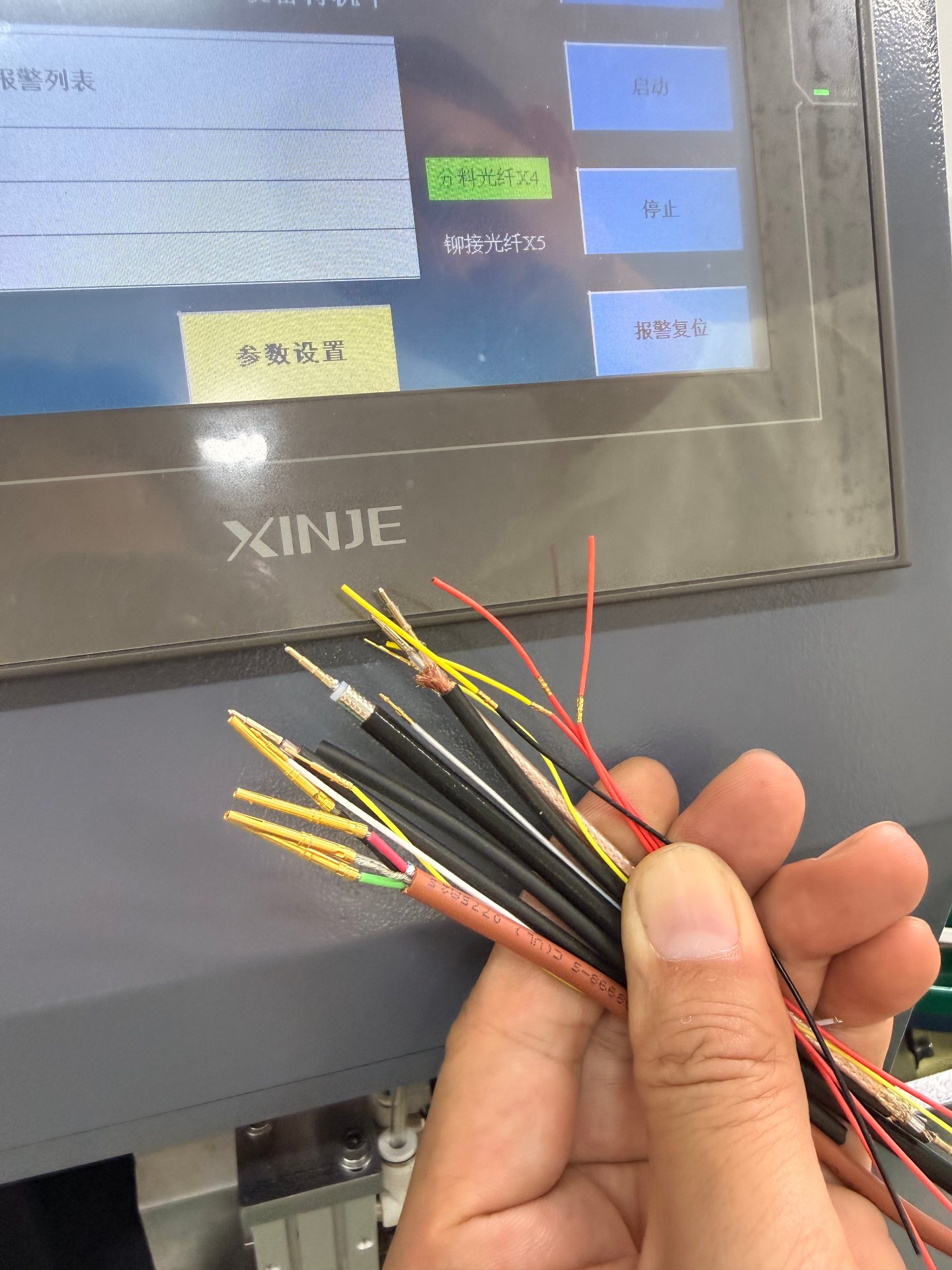 Twist-pin crimping station control screen with crimped micro-connector cable samples held in front of it